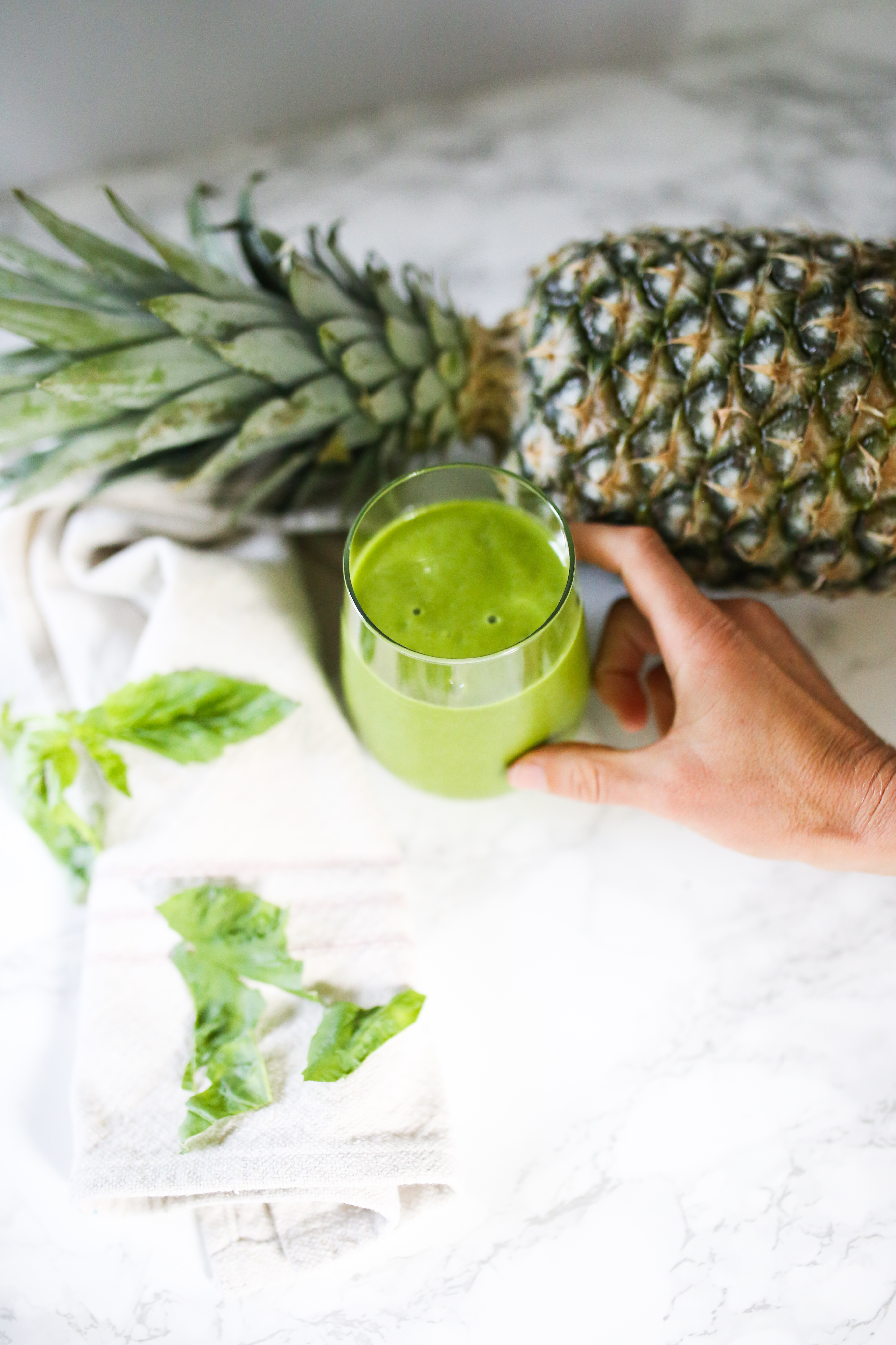 green smoothie with pineapple and basil with hand