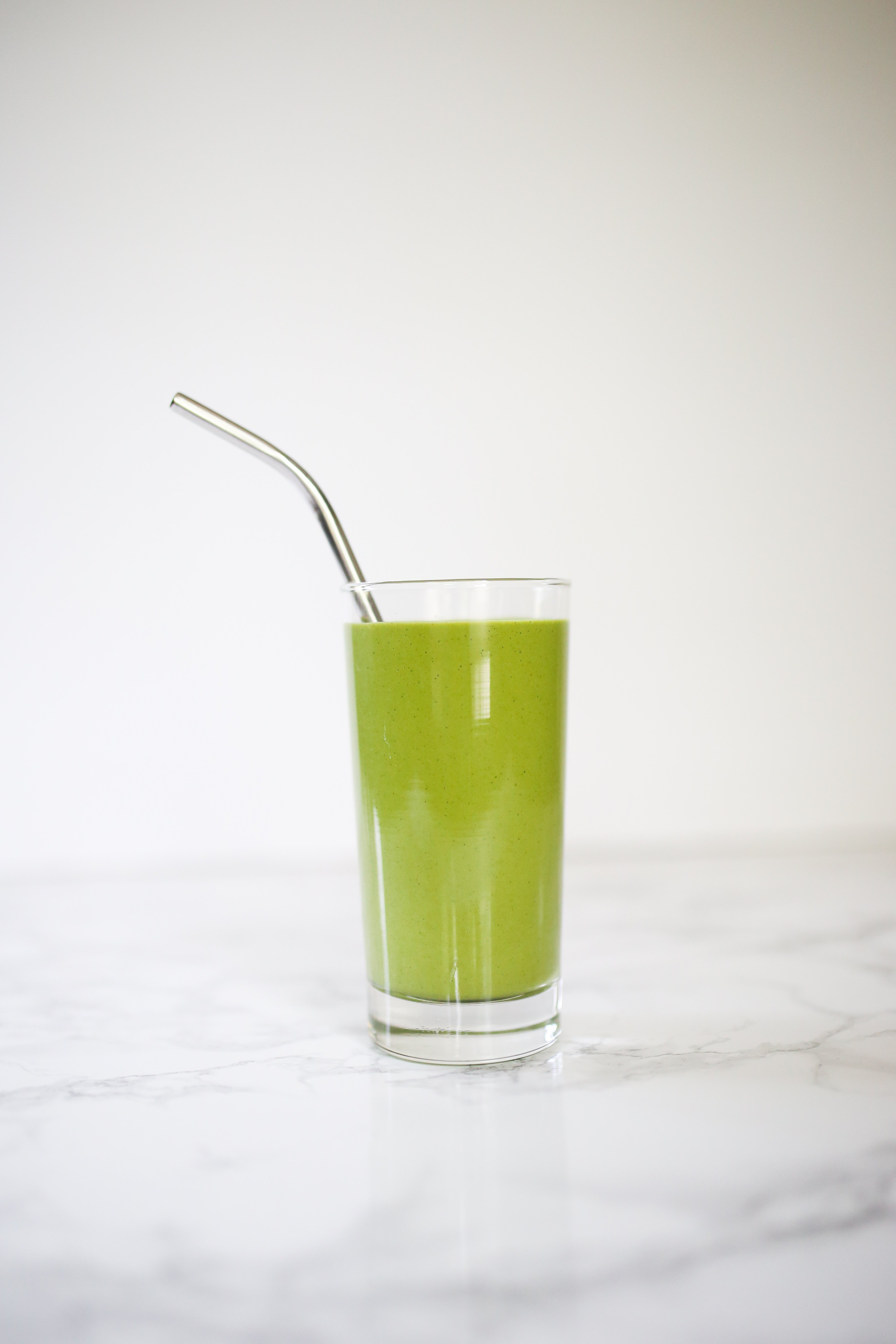 Green Matcha Maca smoothie in tall glass with metal straw