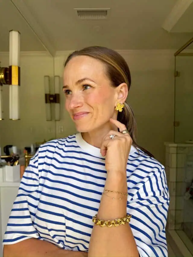 Woman showing cream blush while wearing striped top