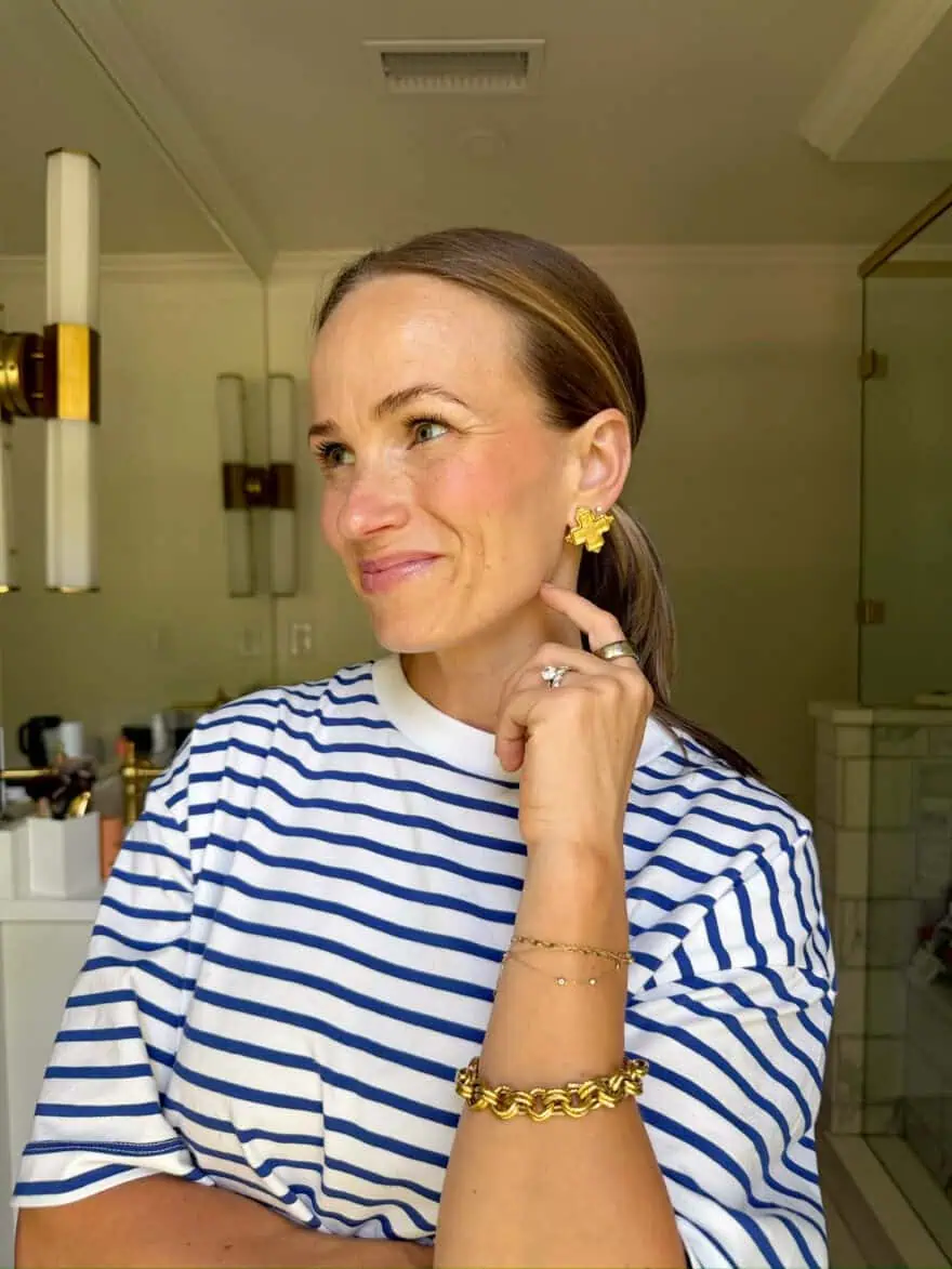 Woman showing cream blush while wearing striped top