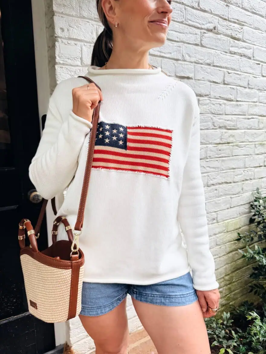 Woman wearing white sweater with Americana flag and denim shorts
