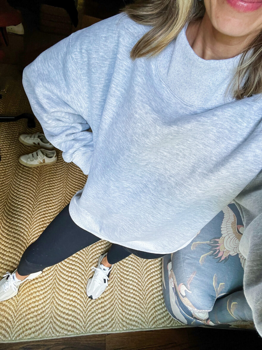 woman showing the details of her High Neck Sweatshirt  and black leggings