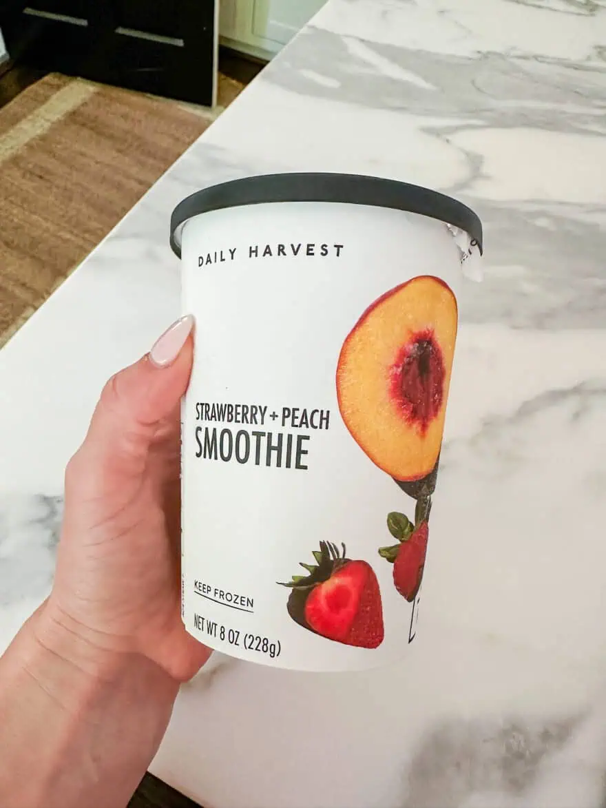 Woman showing Strawberry Peach Daily Harvest Smoothie