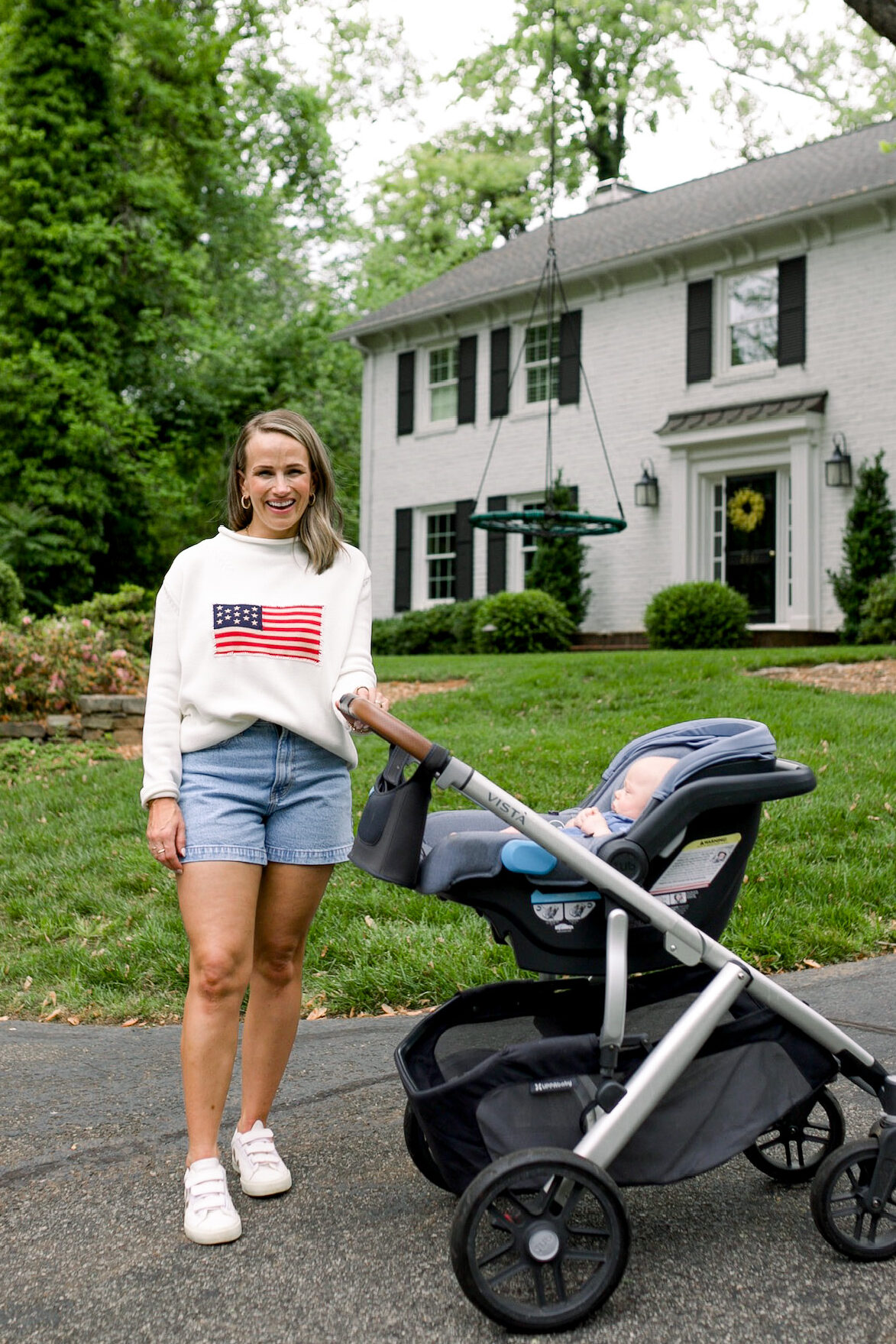 TeriLyn Adams wearing the best denim shorts for moms standing by her baby in a stroller