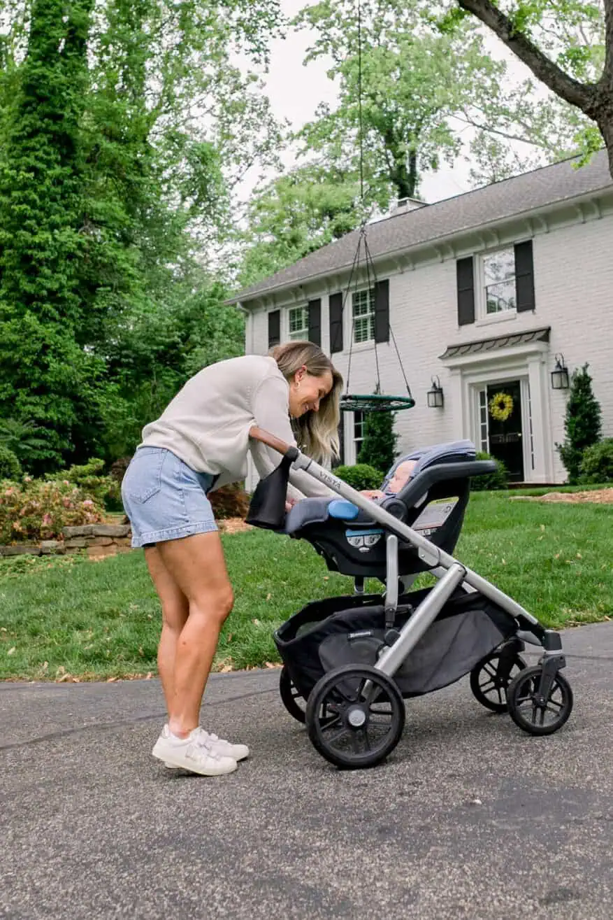 TeriLyn Adams wearing the best denim shorts that are under $100 standing next to stroller
