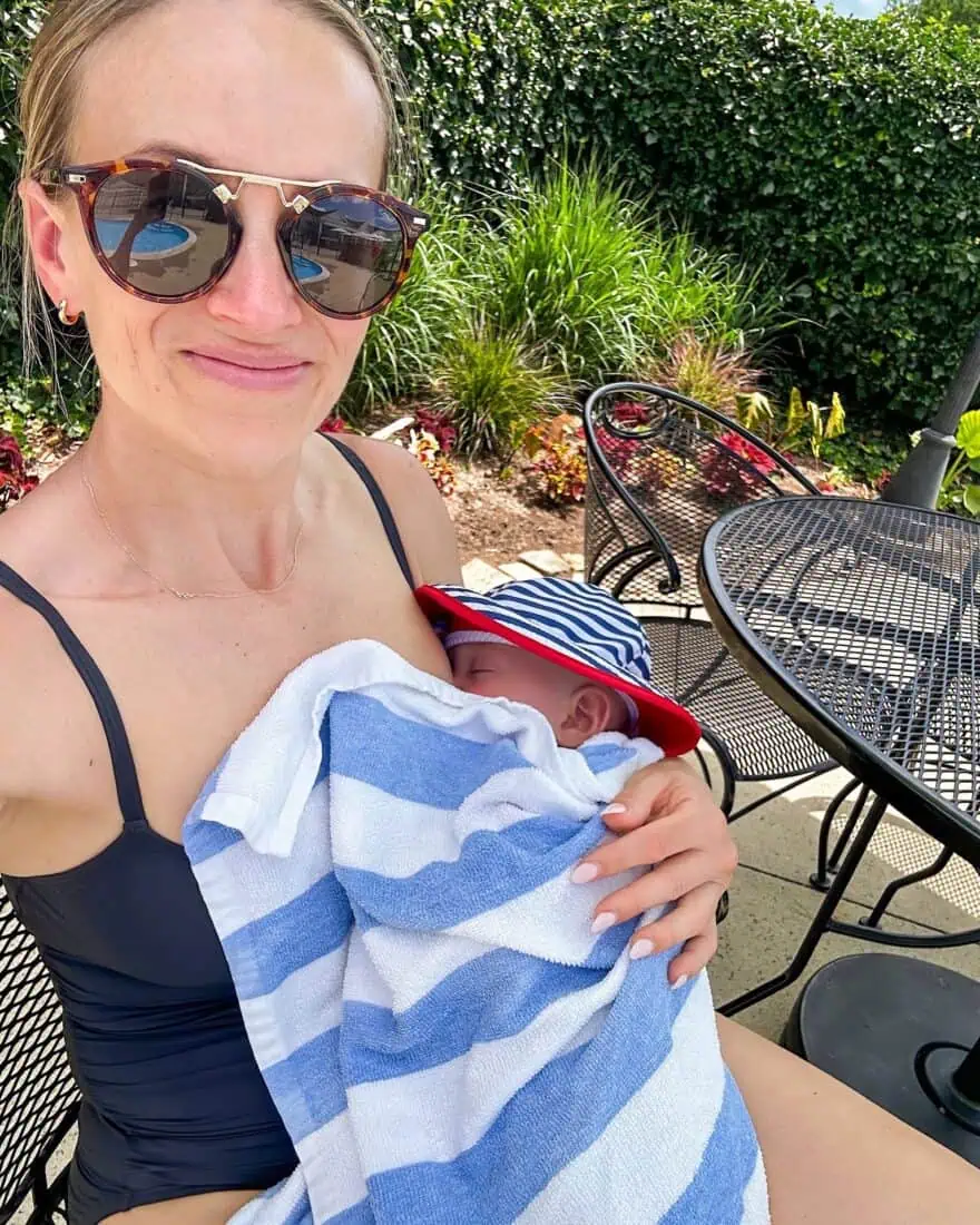 Woman at pool in swimsuit holding baby