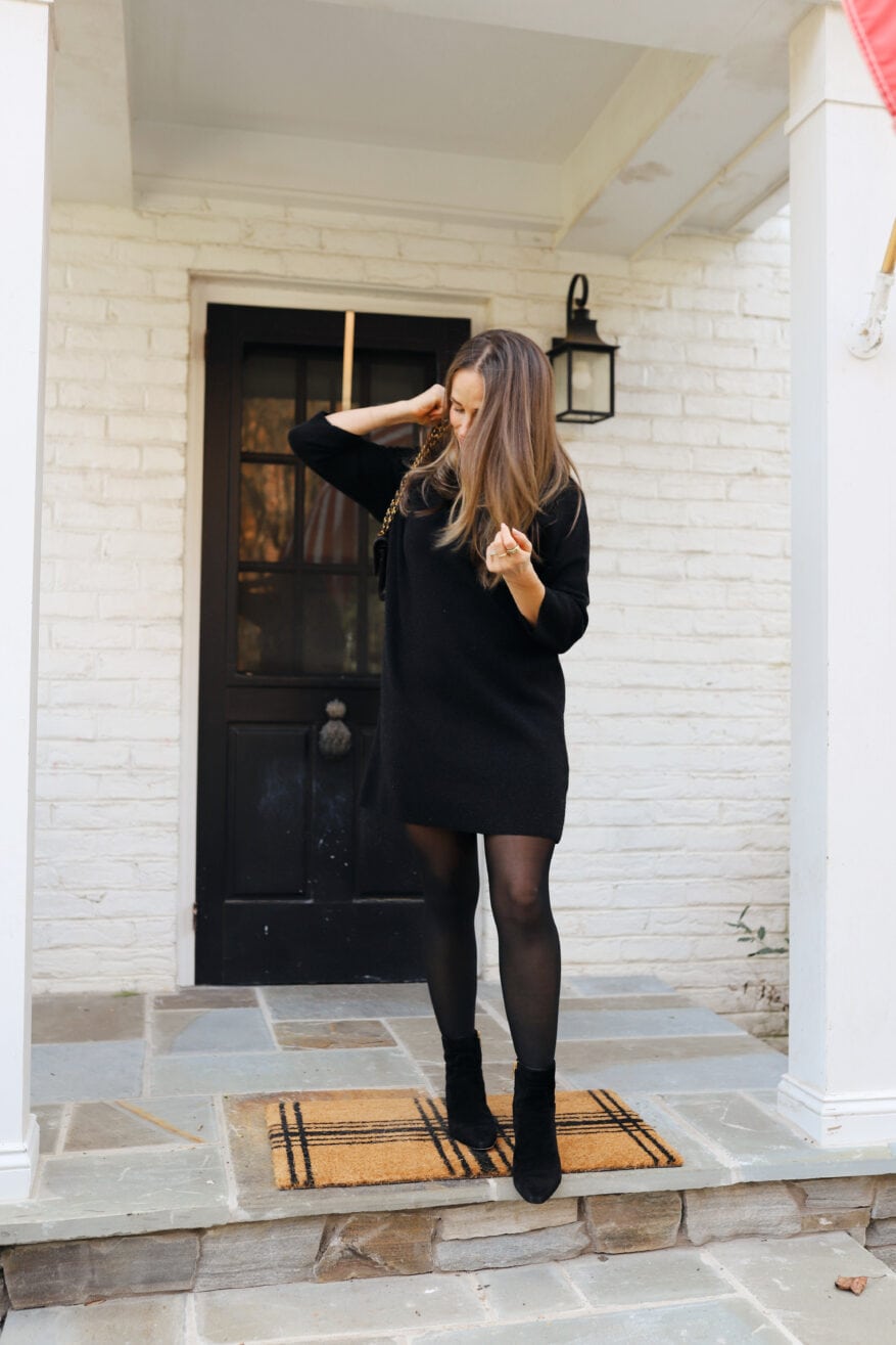 Woman leaving house wearing black knit dress with tights and boots