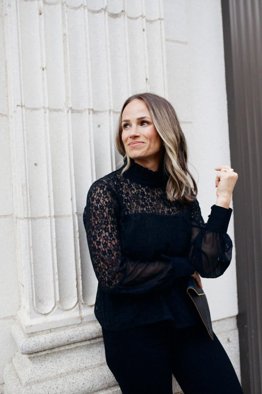 Woman leaning against wall in black lace top and pants