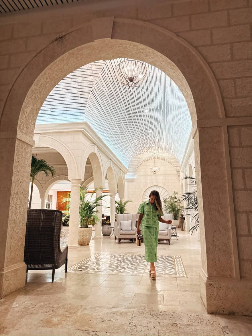 Woman standing in resort lobby wearing matching green top and skirt