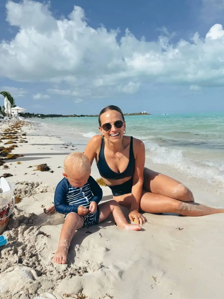 Woman wearing Left on Friday two piece while sitting on beach with son