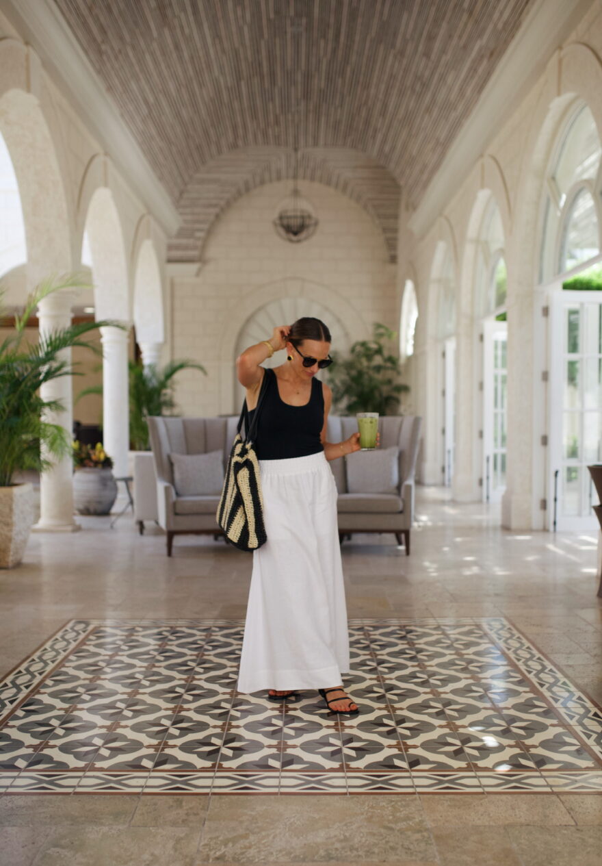 Woman wearing white skirt and black top while standing in lobby of resort