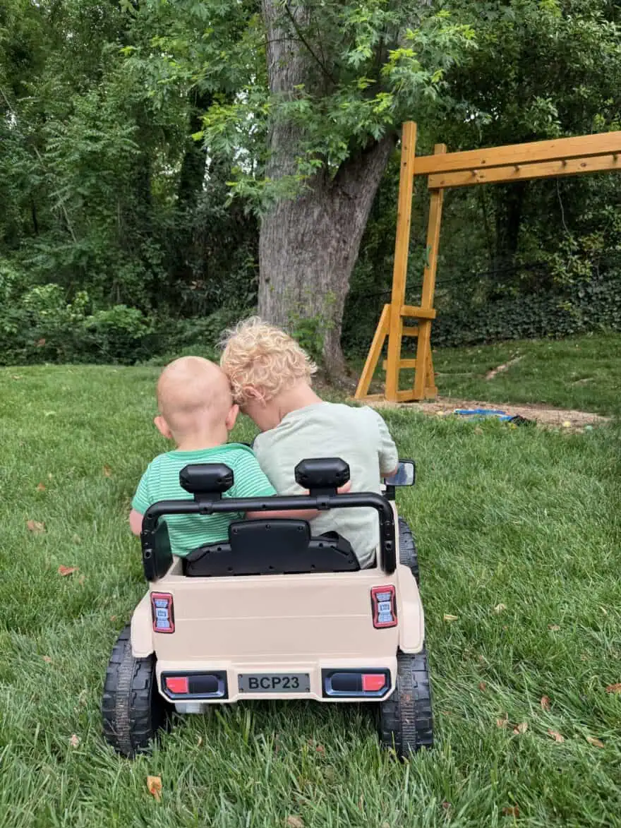 Two young boys riding in kid Jeep