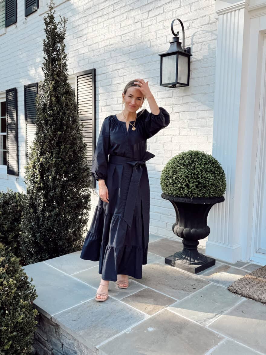Woman wearing blue dress from Tuckernuck while standing on porch