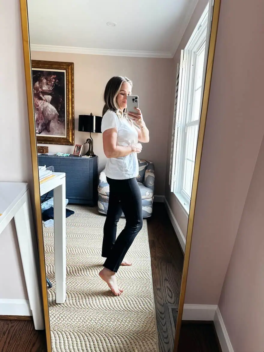 Woman showing side view of Quince black jeans and white top