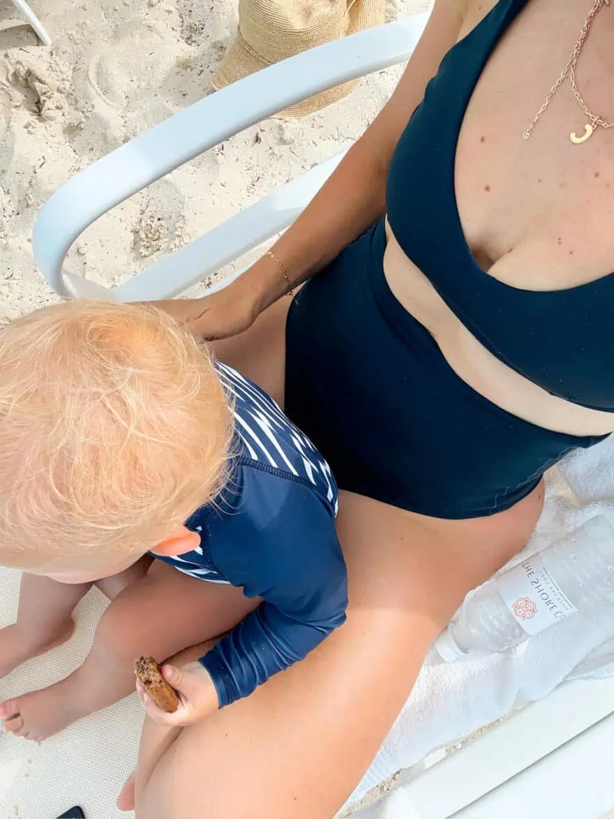 Woman showing close up of navy two piece with baby on her lap