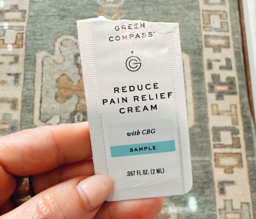 Woman holding sample of Green Compass Reduce Pain Relief cream
