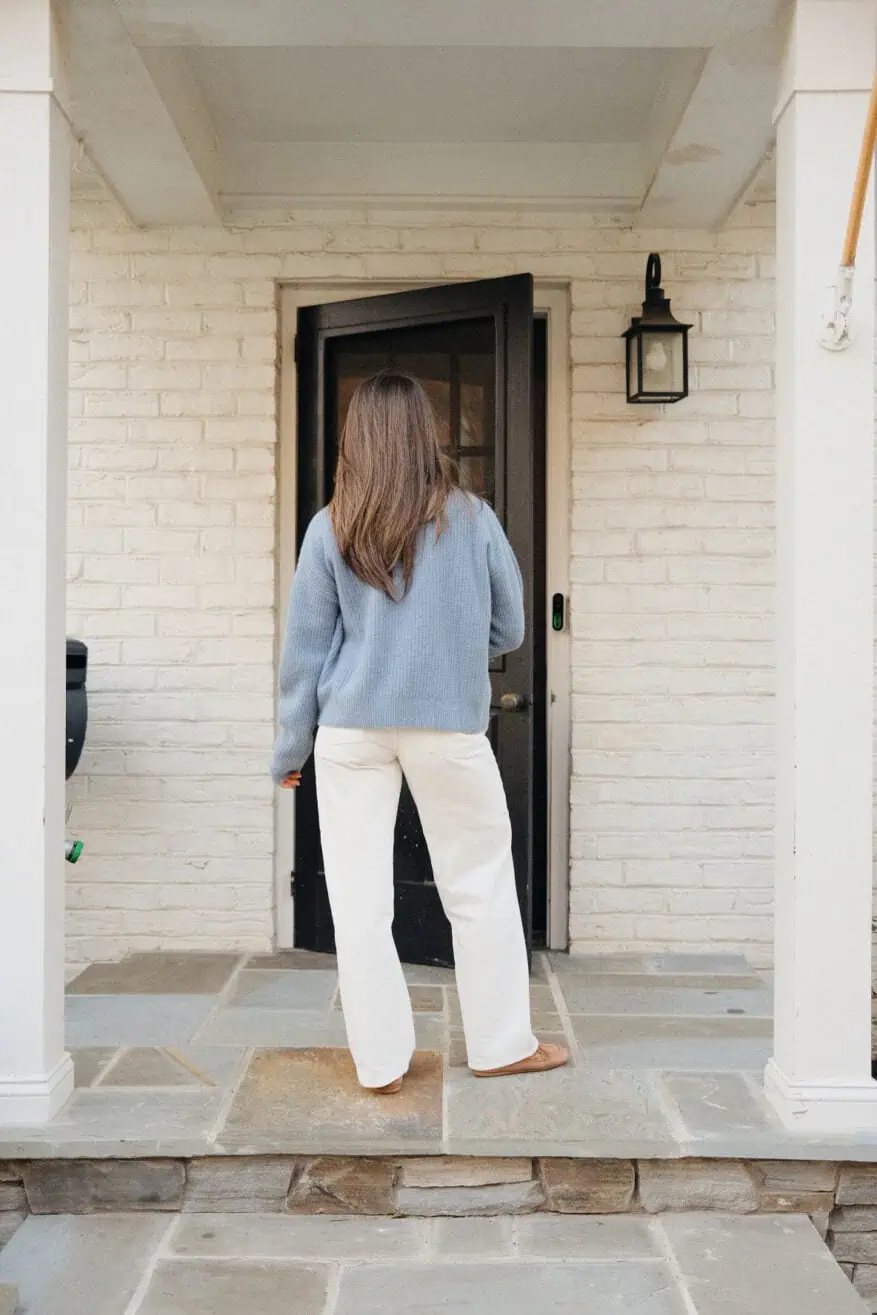 Woman wearing high rise straight leg jeans with blue sweater and showing back view