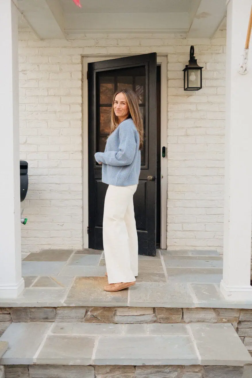Woman wearing wide leg white jeans with blue sweater