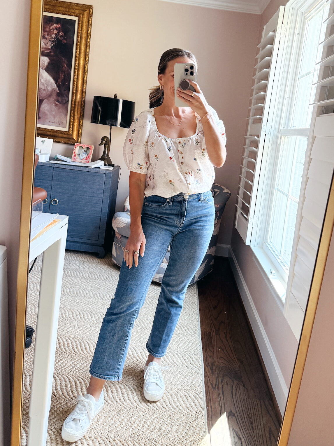 Woman wearing Cariuma OCA Low white sneakers with jeans and a floral top