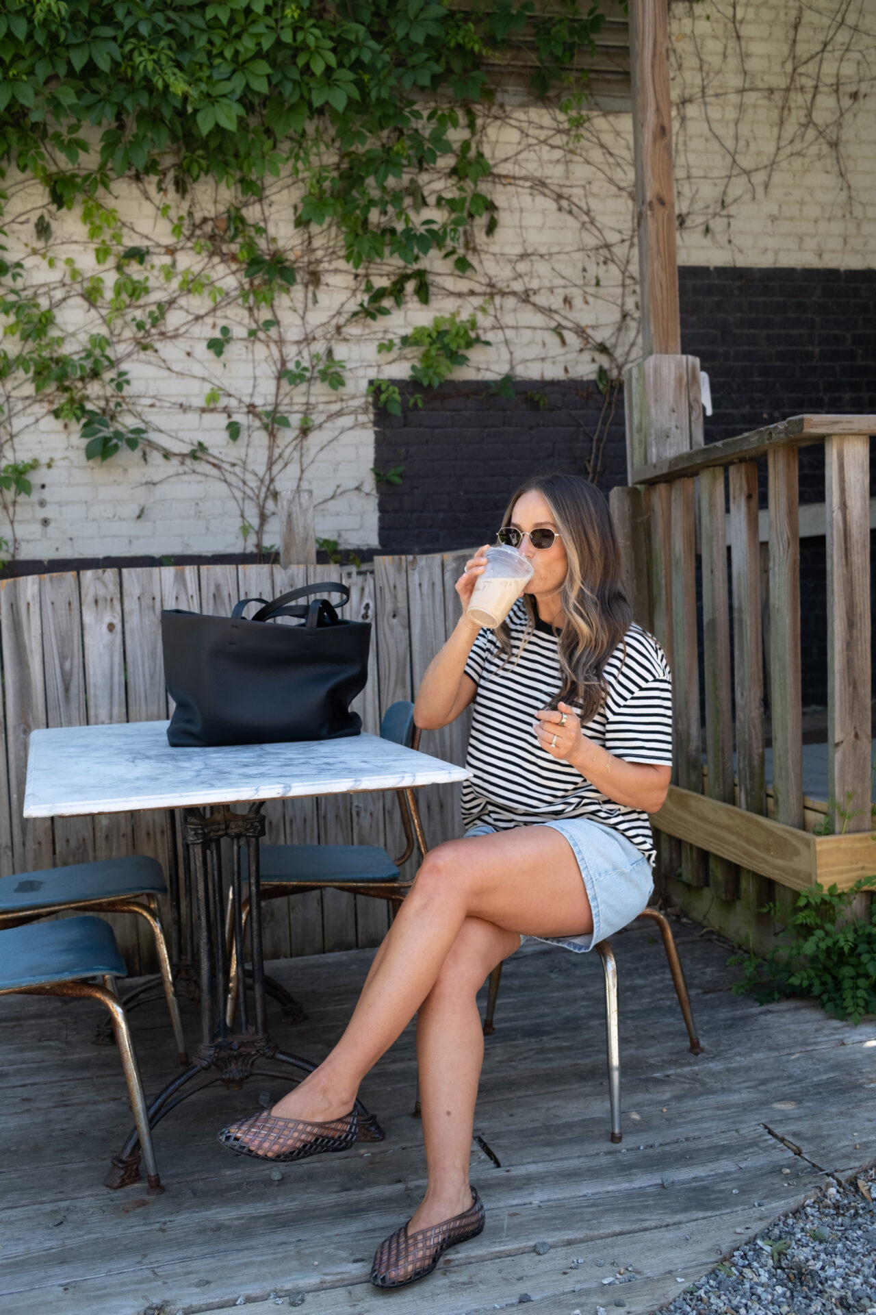 TeriLyn Adams sipping coffee wearing Abercrombie lose shorts and stripe tee with jelly shoes.