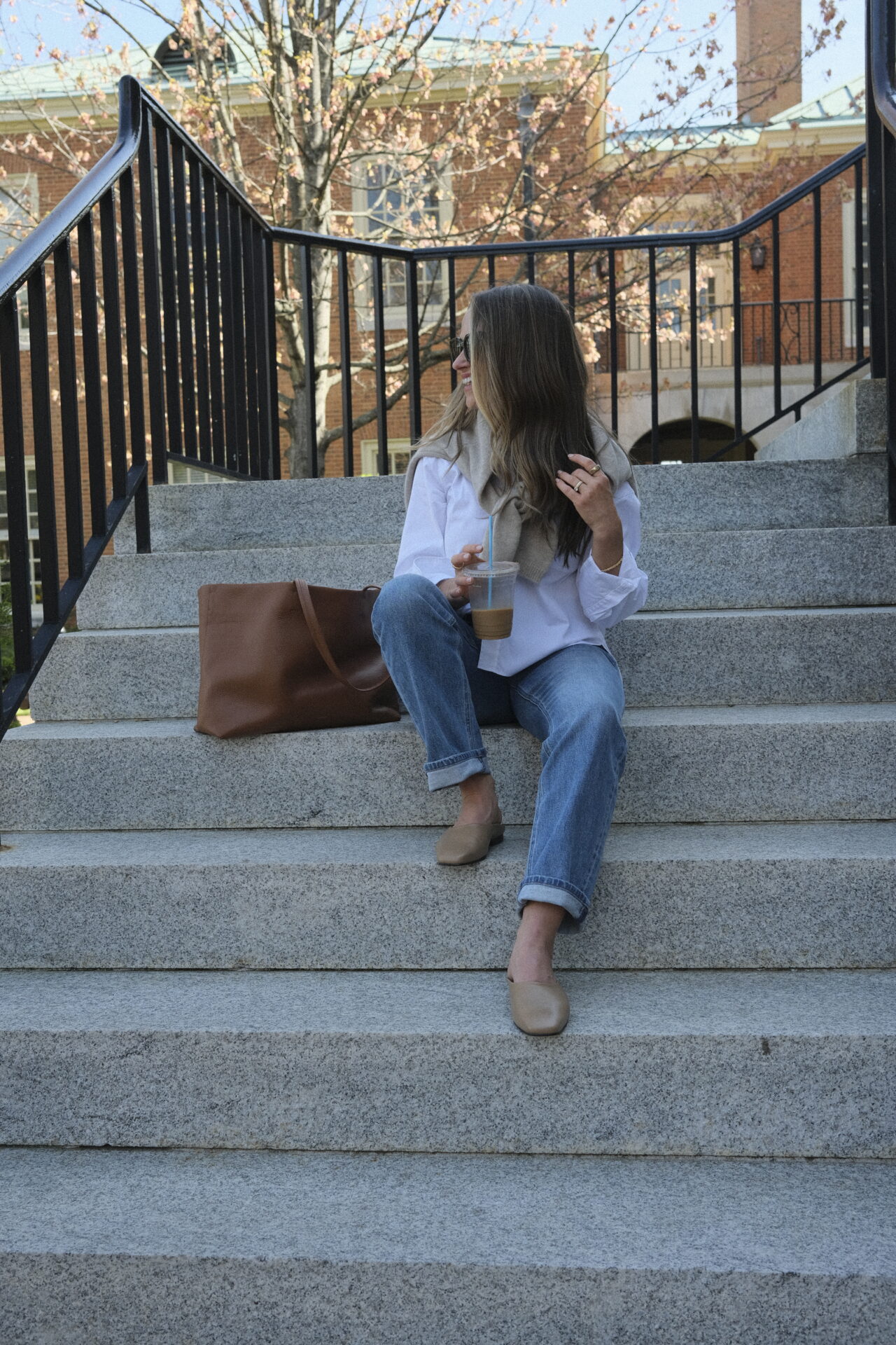 TeriLyn Adams sitting on stairs in jeans and white button down with Cuyana leather tote.