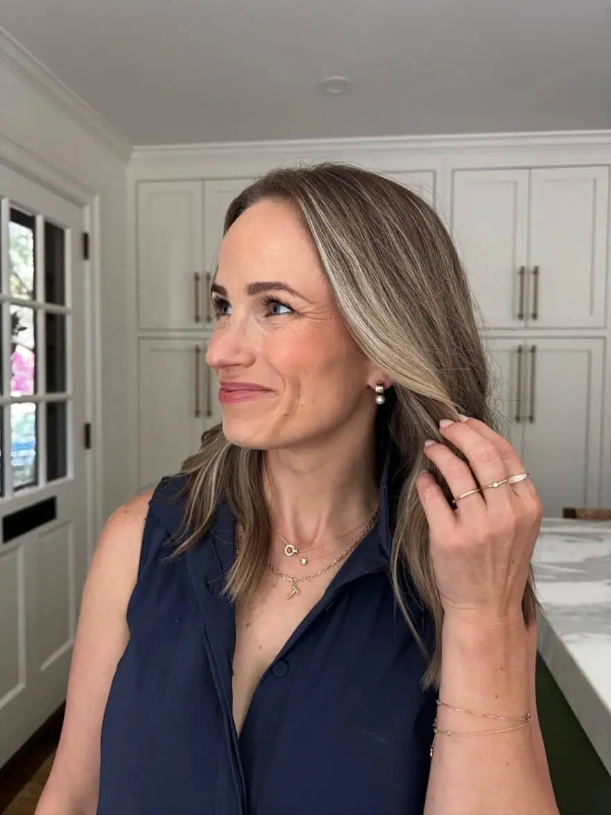TeriLyn Adams in navy top wearing Mejuri pearl drop earrings layered gold necklaces and gold rings