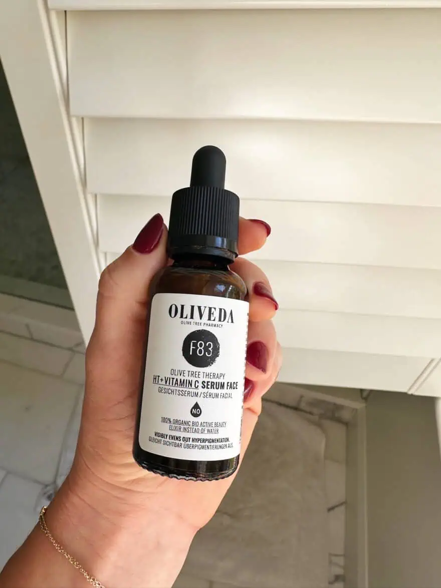 Woman holding bottle of Oliveda Vitamin C serum for the face