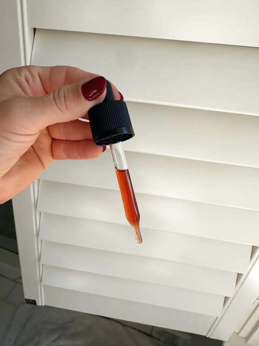 Woman showing dropper filled with Vitamin C serum