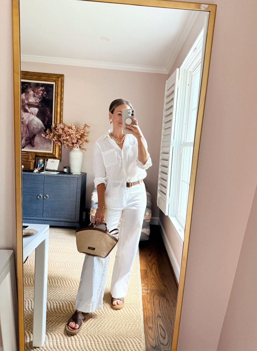 Woman accessorizing a linen outfit with gold jewelry and a straw bag