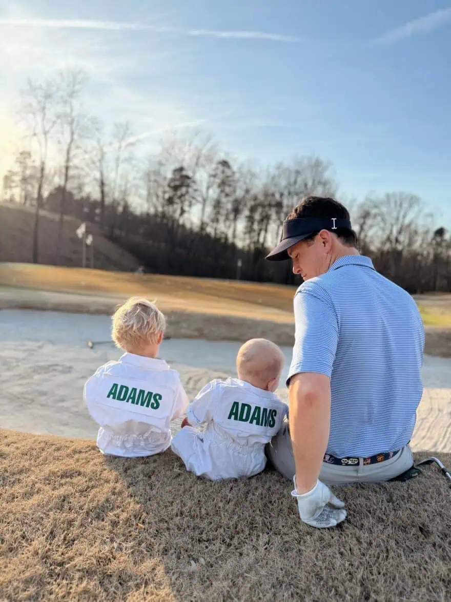 Man sitting on golf course with toddler and baby