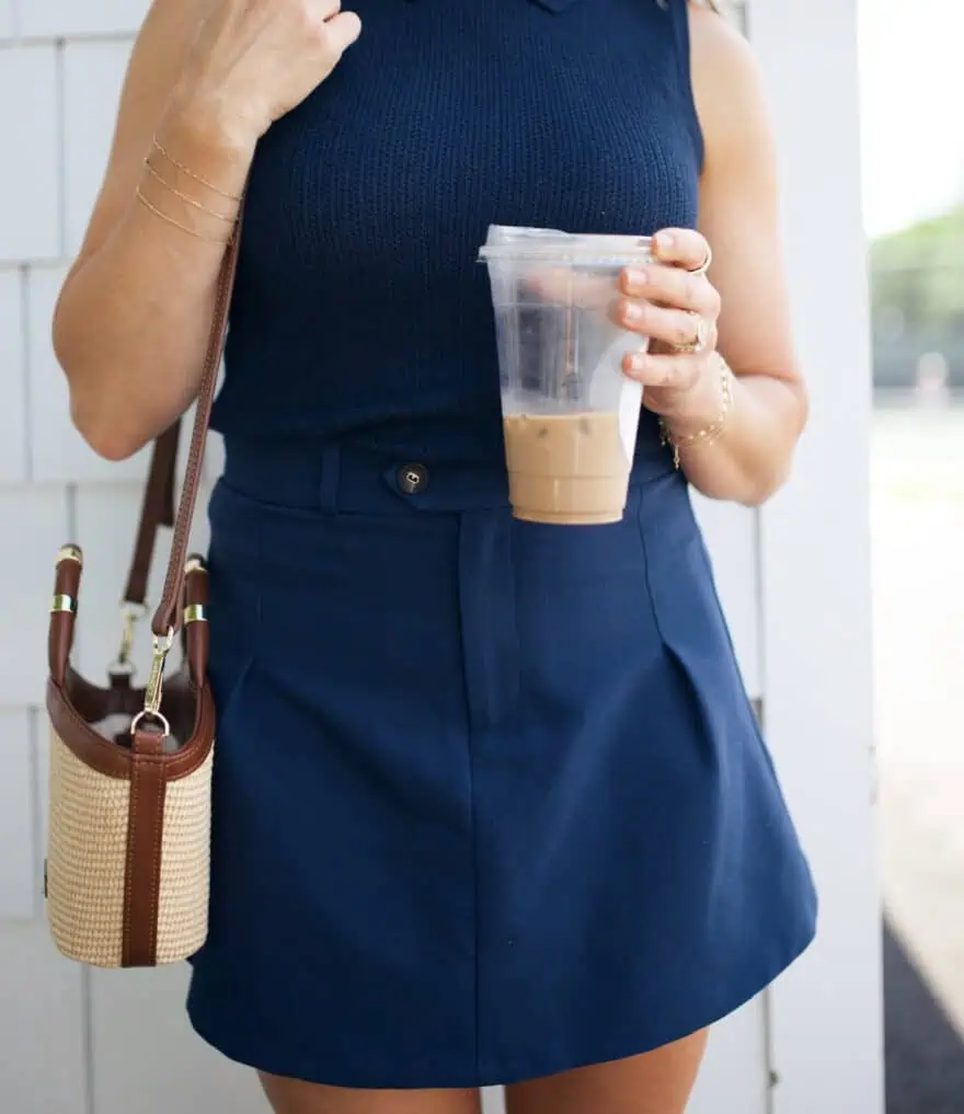 Woman holding coffee while wearing navy skort outfit