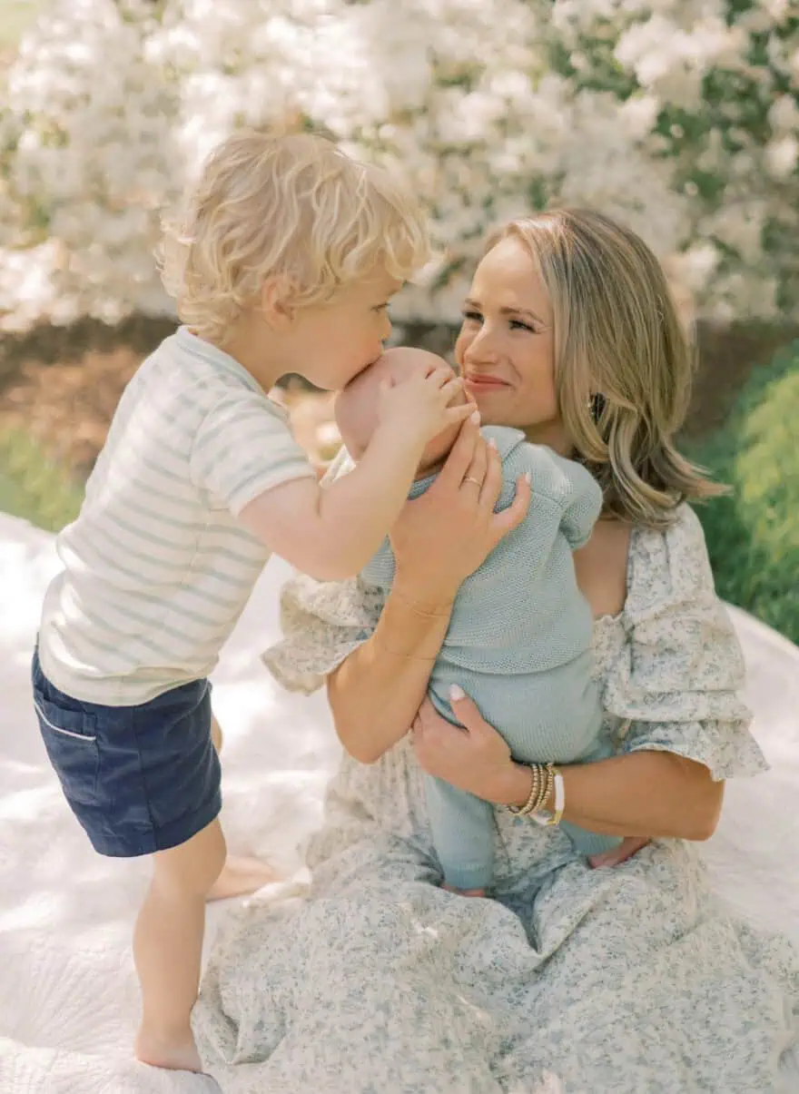 Woman wearing floral dress while holding baby and toddler