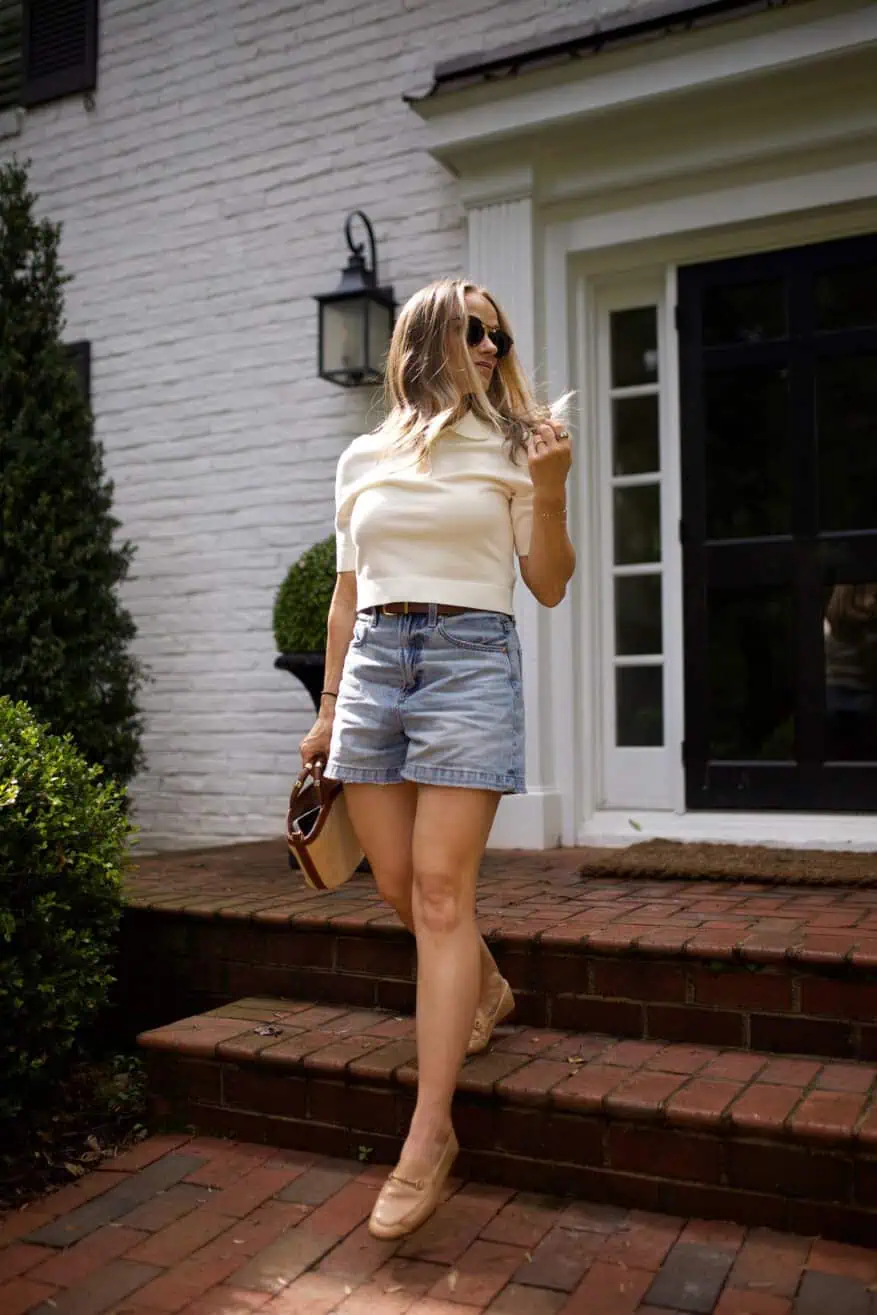Woman walking down stairs in white top and denim shorts