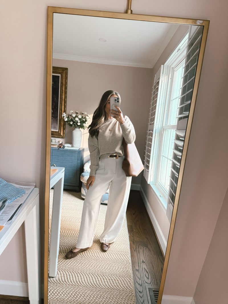 TeriLyn Adams wearing a cream crew neck sweater, ivory trousers, and a blush shoulder bag