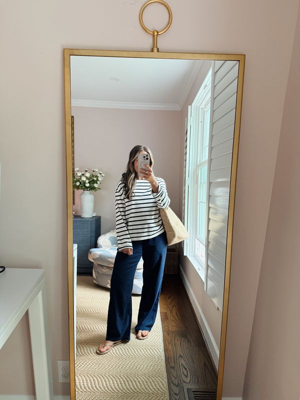 TeriLyn Adams wearing a striped long sleeve top, navy linen pants, and sandals with a tan tote