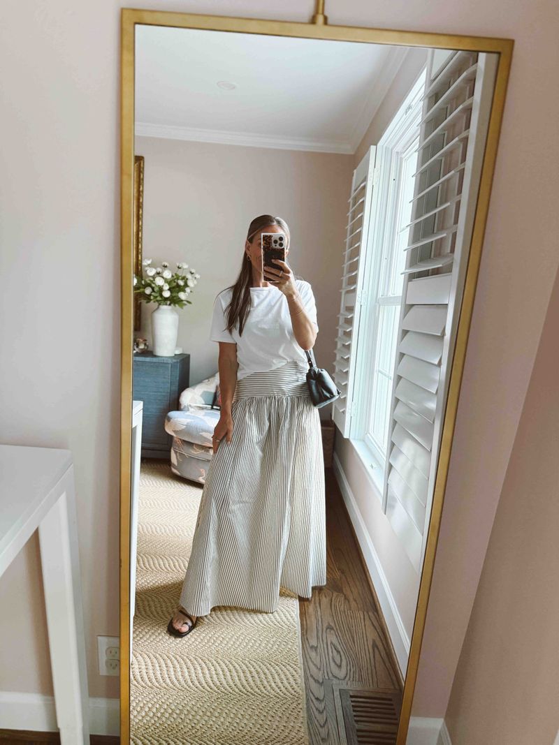 TeriLyn Adams wearing a white tee, striped maxi skirt, sandals, and a black crossbody bag