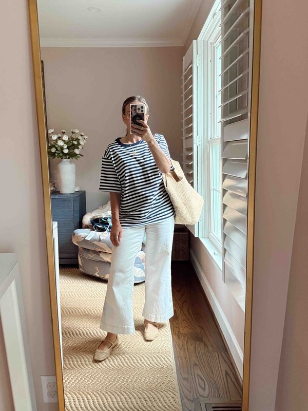 TeriLyn Adams wearing an oversized striped tee, white jeans, and woven flats with a straw tote