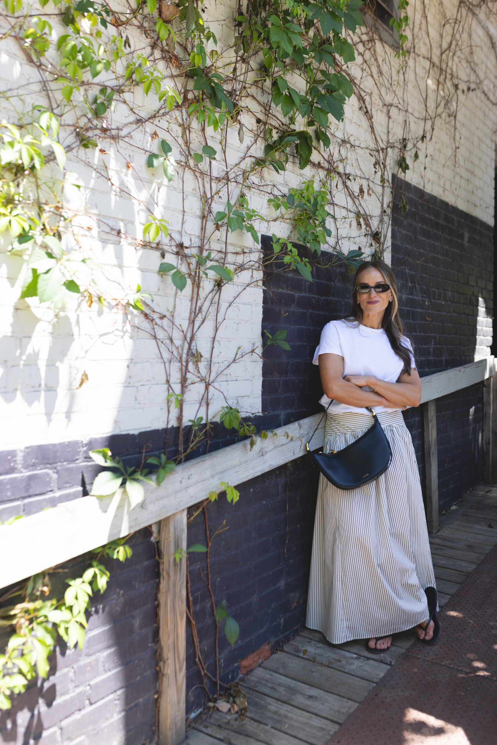 TeriLyn Adams wearing a Universal Thread Boyfriend T-Shirt and CAARA Vashti Skirt beside an ivy-covered wall