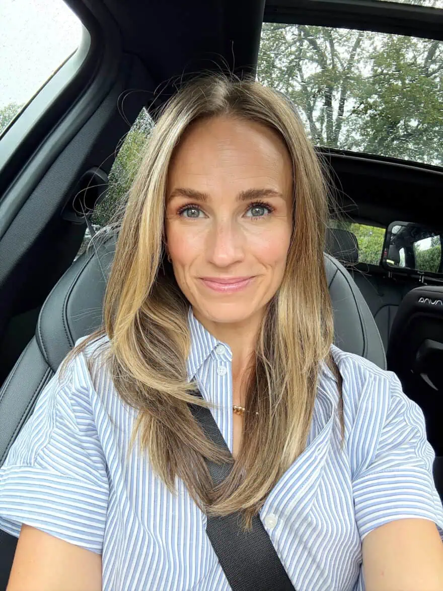 Woman sitting in a car in blue top with hair down