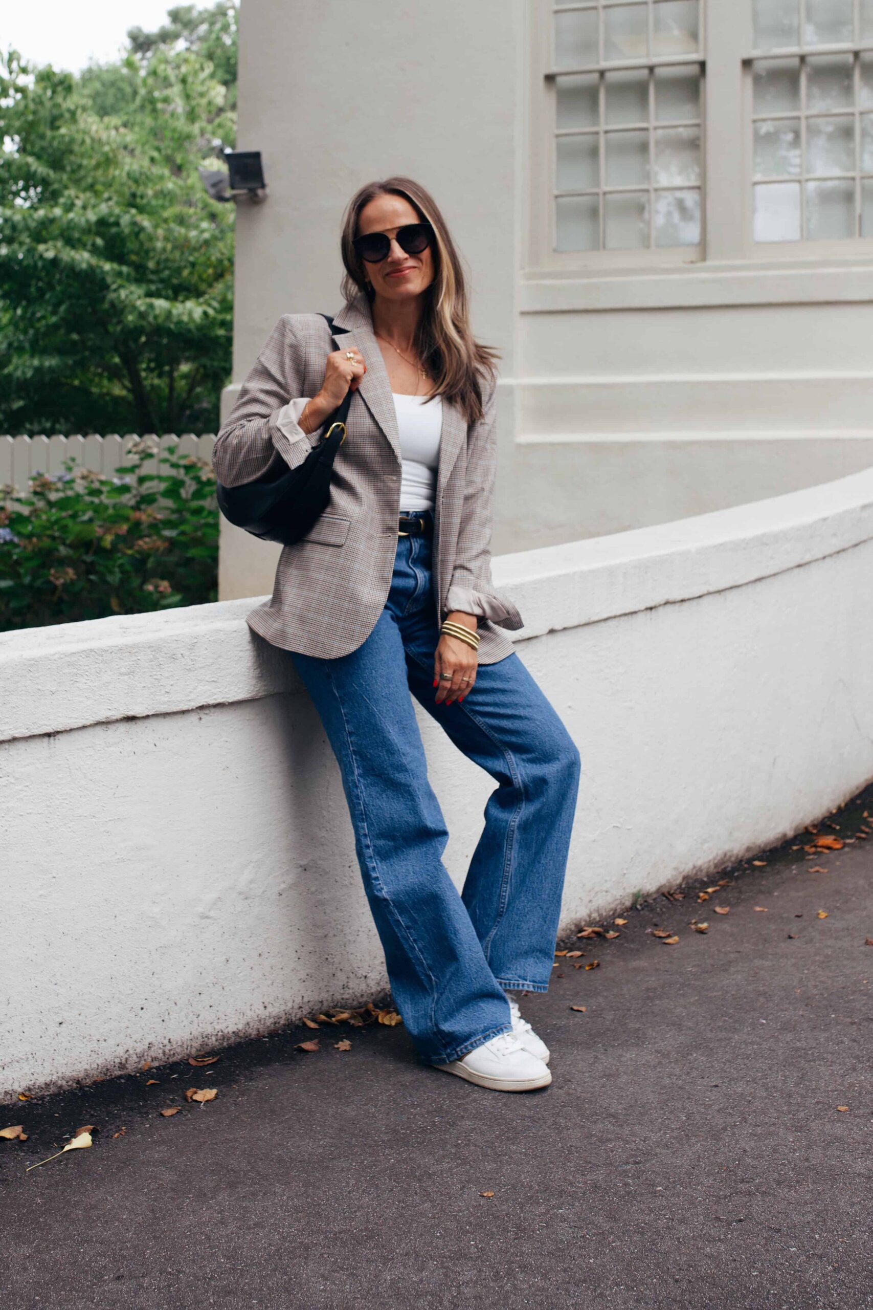 woman sitting in abercrombie 90s high rise 90s jeans with blazer and sunglasses 