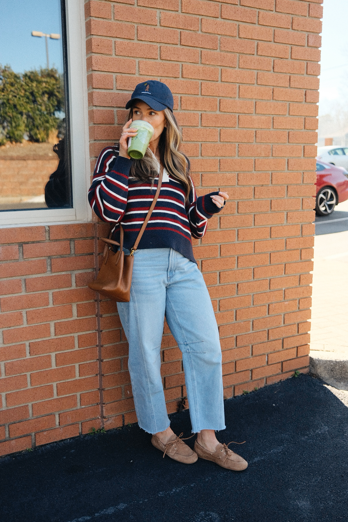 TeriLyn Adams drinking iced coffee in a striped sweater and Loft barrel jeans with Sperry boat shoes