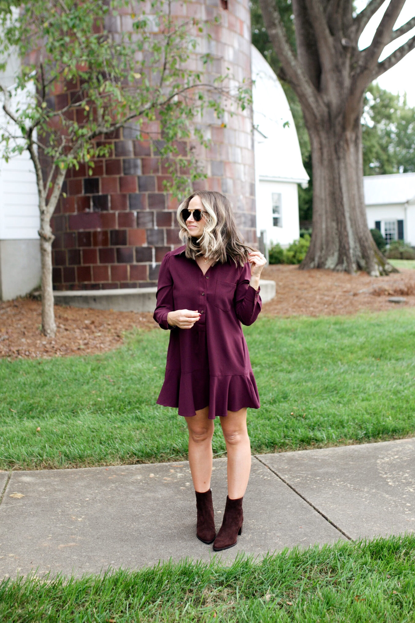 Woman wearing wine colored dress with booties and wearing sunglasses