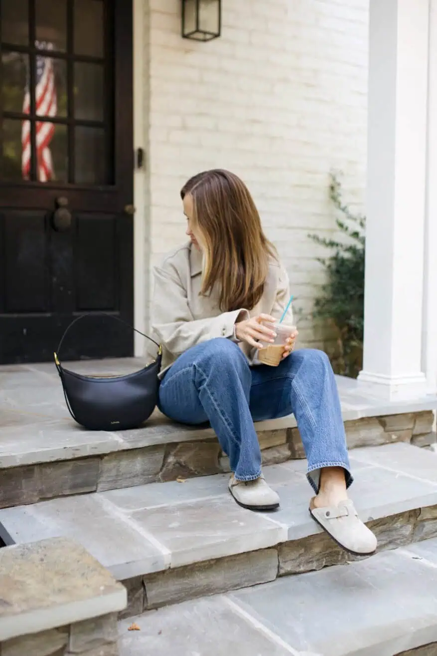 Woman sitting on stairs wearing jeans and Birkenstock clogs