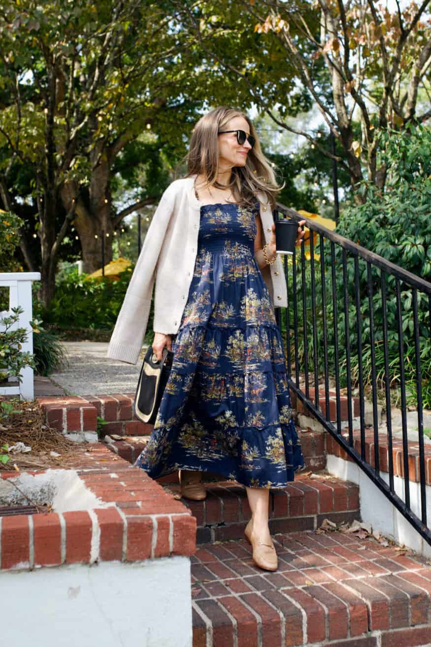 Woman walking down brick stairs in dress, loafers, and a jacket