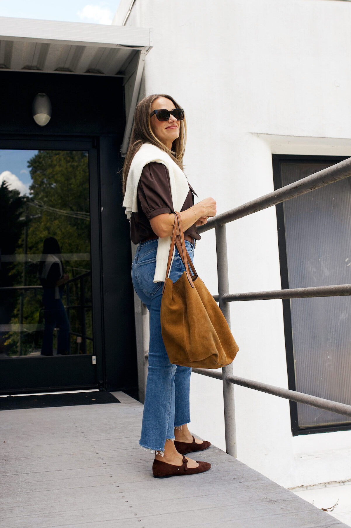 Woman wearing draped sweater over top with denim and ballet flats