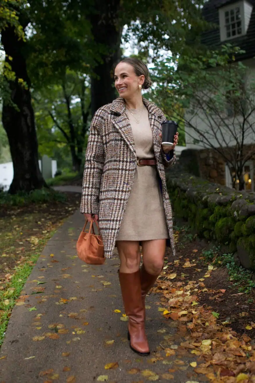 Woman walking along a path in a sweater dress, jacket, and Loeffler Randall Goldy Tall Leather Boots from Tuckernuck