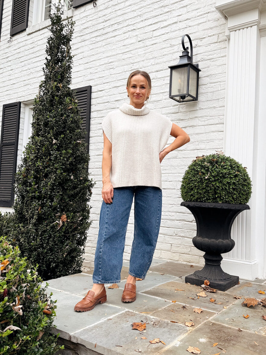 TeriLyn Adams wearing a sleeveless turtleneck sweater, barrel jeans, and brown loafers