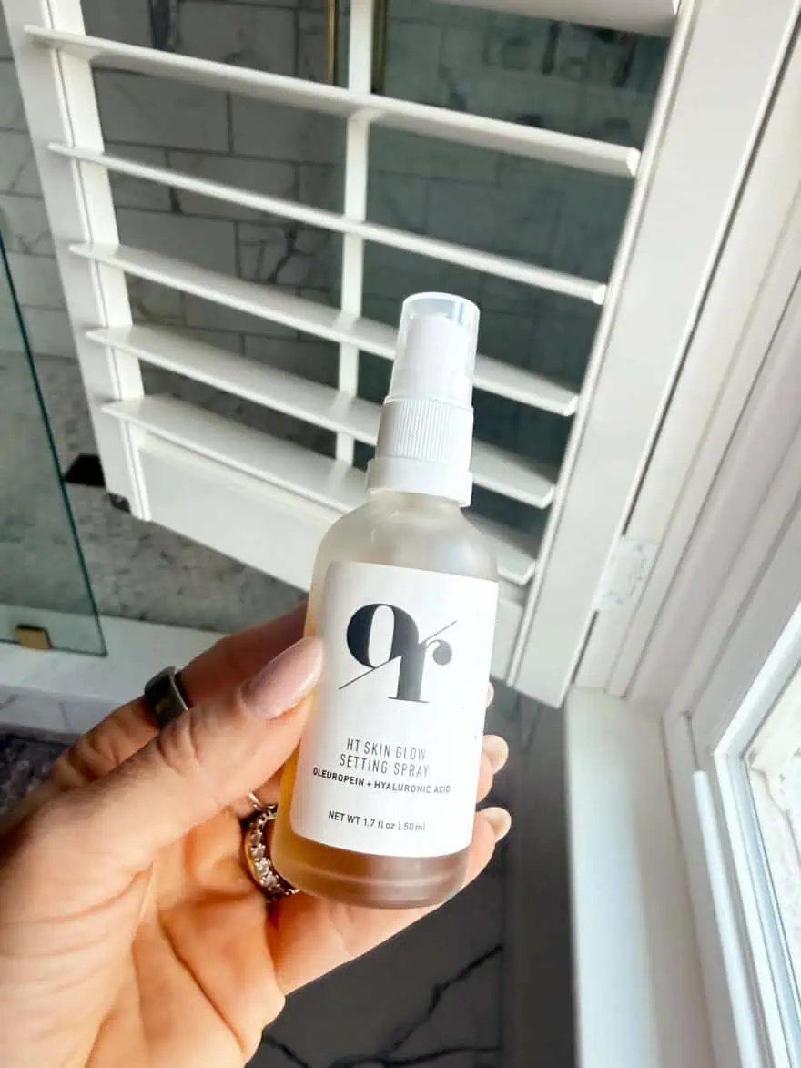 Woman holding HT Skin Glow Setting Spray bottle