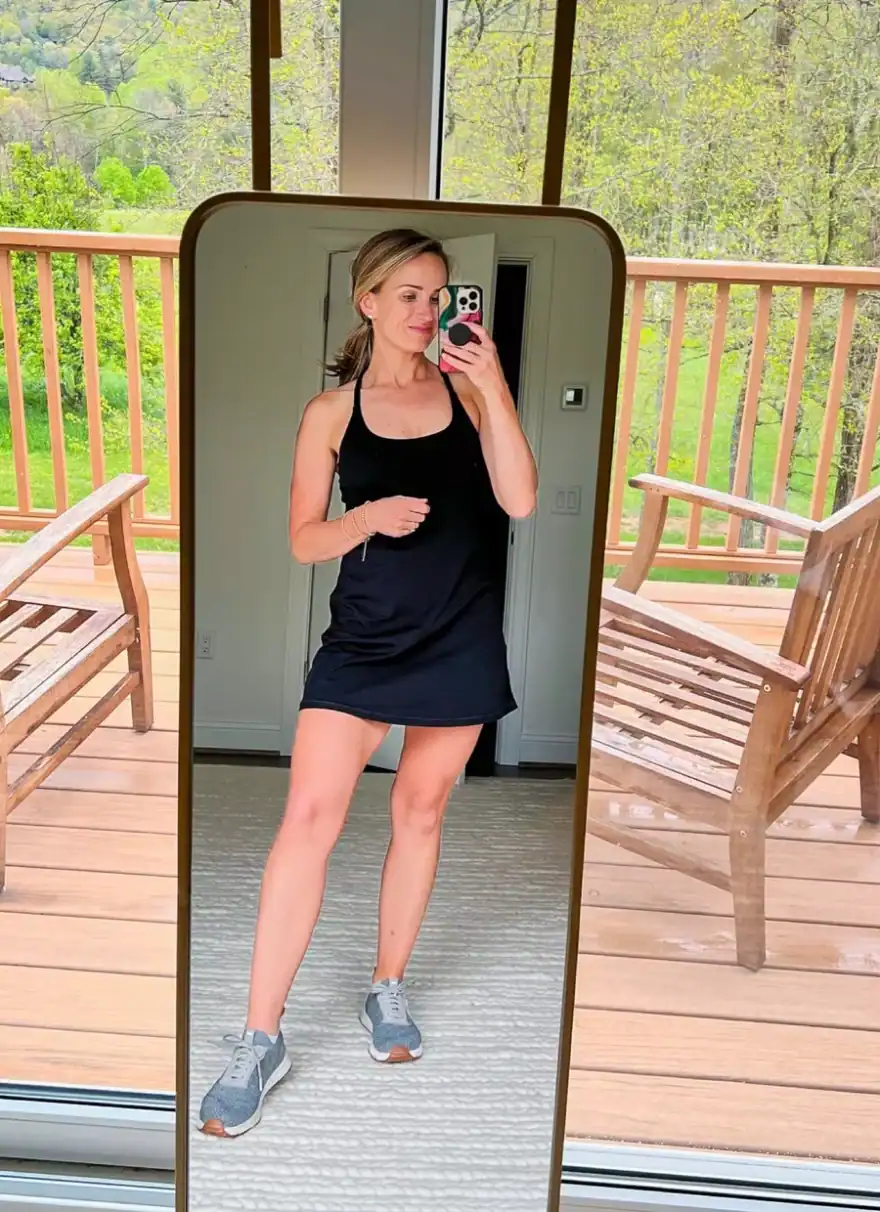 Woman taking a selfie in an athletic dress and tennis shoes
