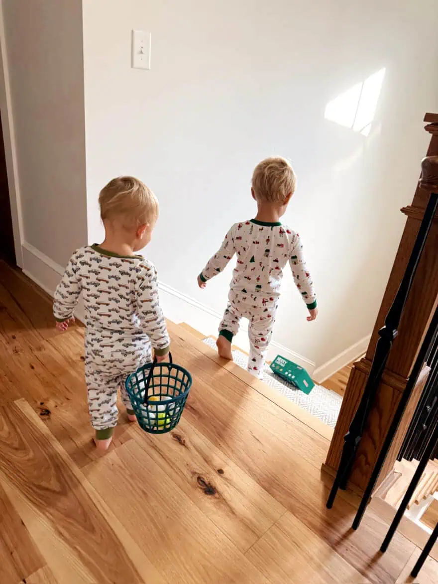 Two young boys wearing matching pajamas walking down stairs